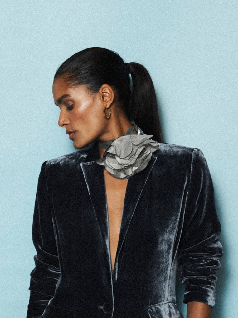 Woman wearing a black velvet outfit against a light blue background