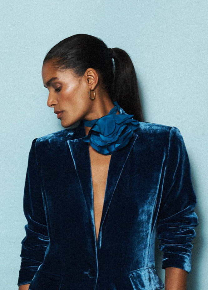 Woman wearing a blue velvet outfit against a light blue background